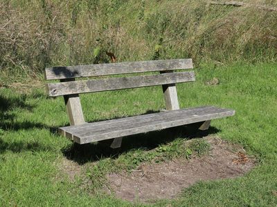 A bottle of water and a towel on a bench.